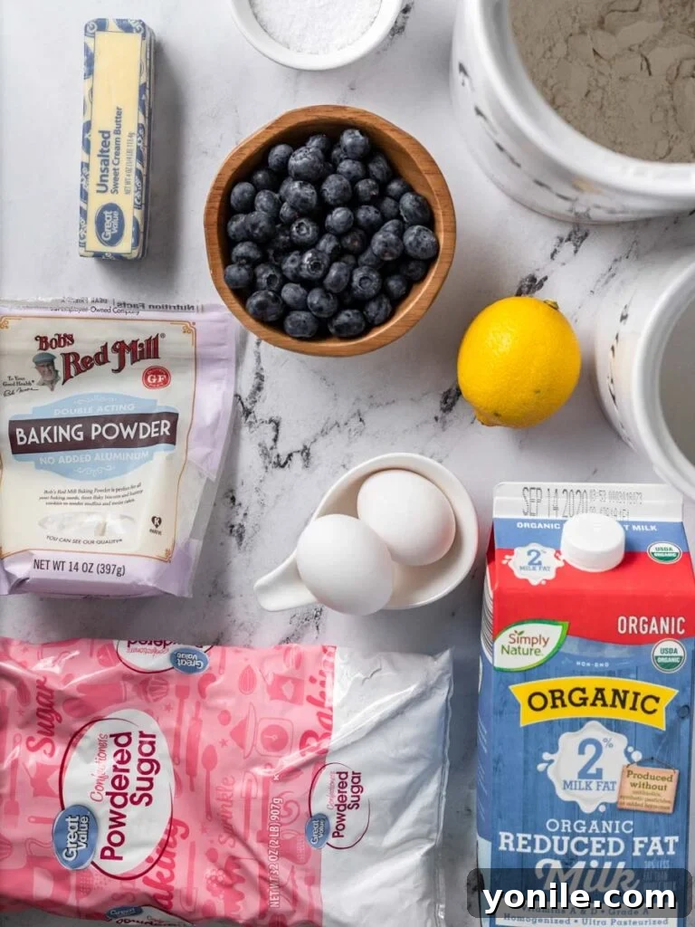 Bright Lemon Blueberry Bread 3 A flat lay photograph displaying all the fresh ingredients for making Lemon Blueberry Bread, including flour, sugar, eggs, butter, lemons, and blueberries.