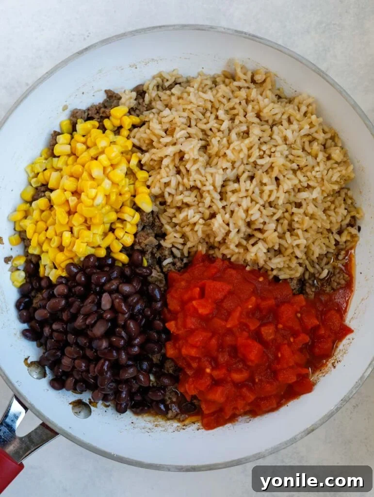 beans, tomatoes, rice and corn in a skillet.