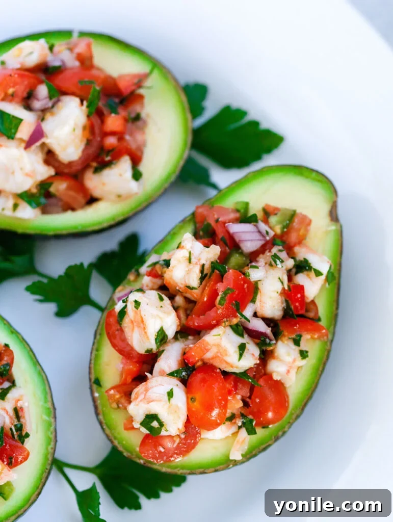 Shrimp Stuffed Avocado on a white plate, garnished with fresh herbs.
