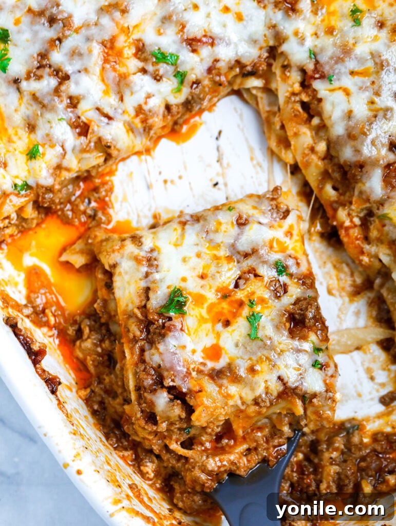 Hearty Beef Lasagna 2 slice of Meat Lasagna being taken from a dish with a spatula, revealing delicious layers of pasta, meat sauce, and cheese.