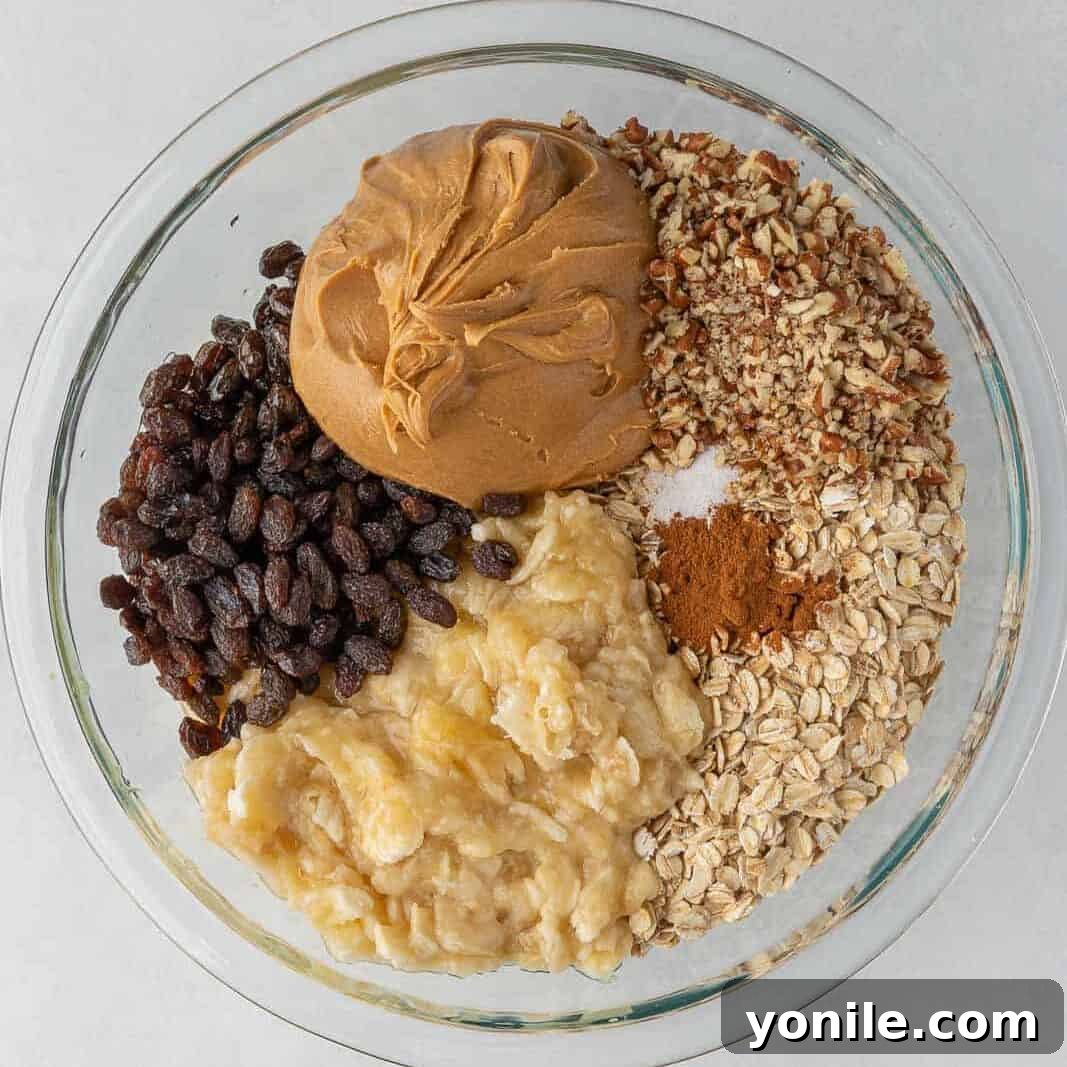 All the cinnamon raisin oatmeal bar ingredients mixed together in a clear glass bowl, showcasing the rich texture.