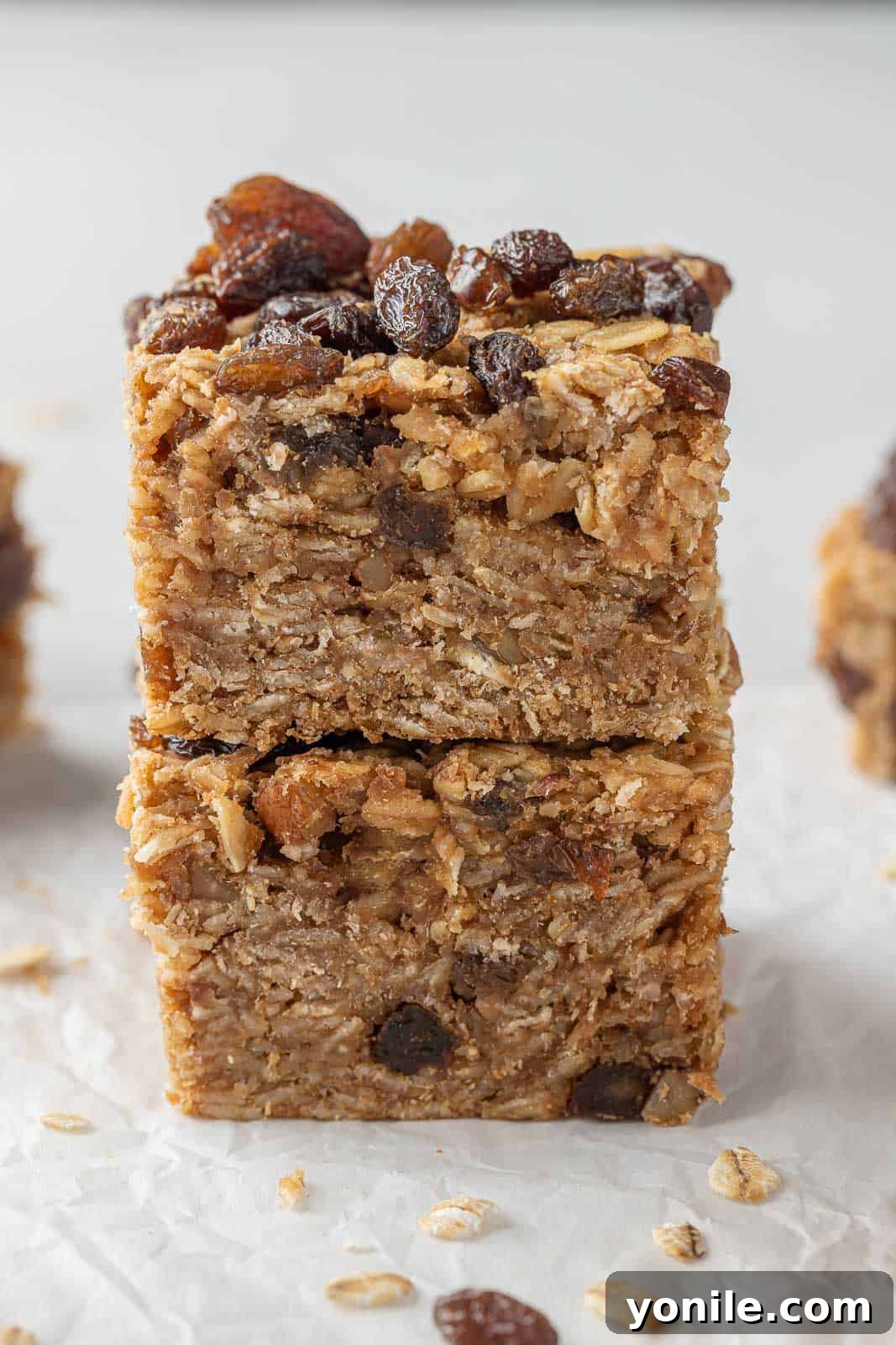 Two soft and chewy cinnamon raisin oatmeal bars stacked on top of each other, ready for a delicious bite.
