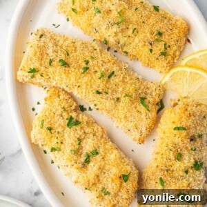 Baked cod fillets on a plate garnished with parsley and lemon slices.