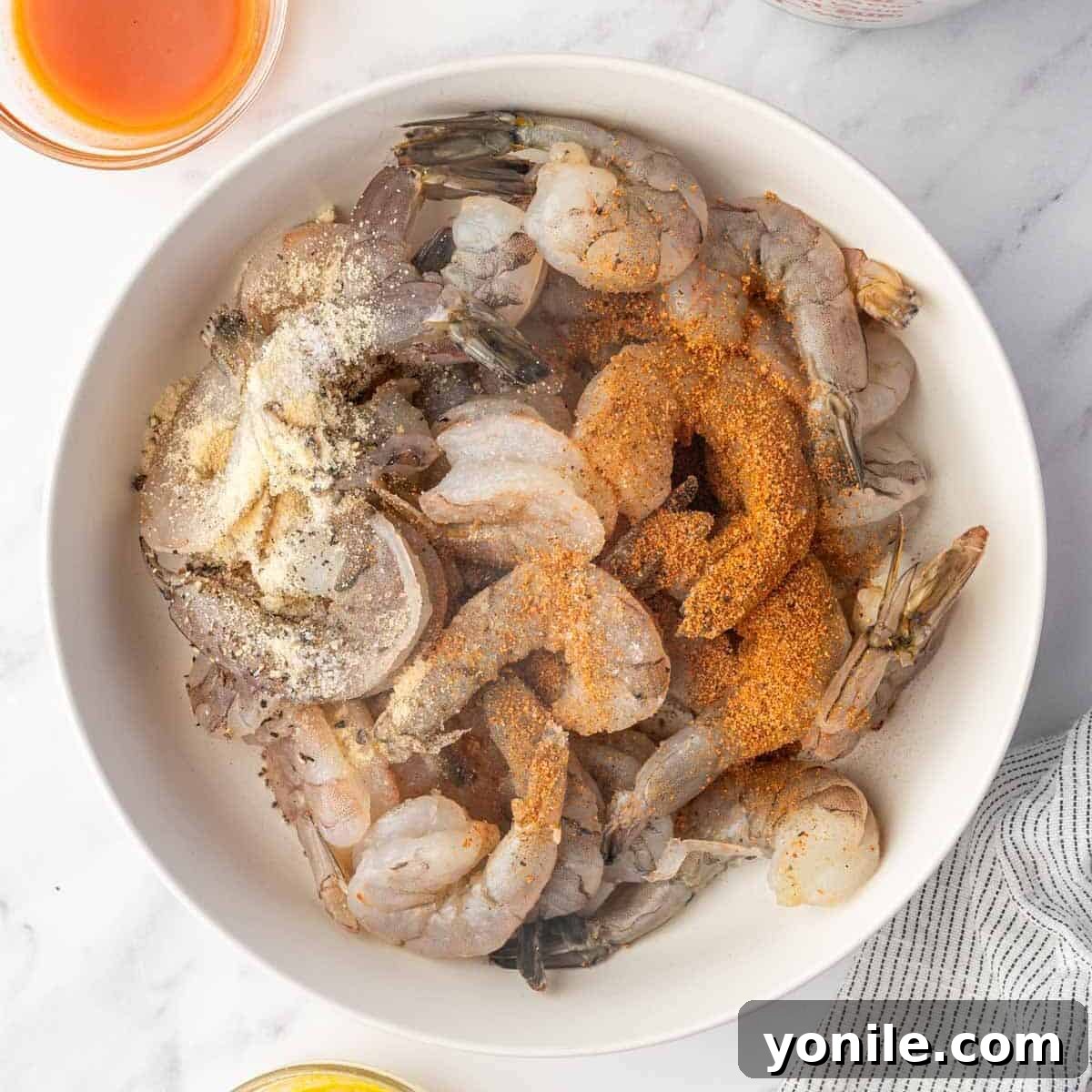 Shrimp seasoned with cajun seasoning and other spices in a bowl.