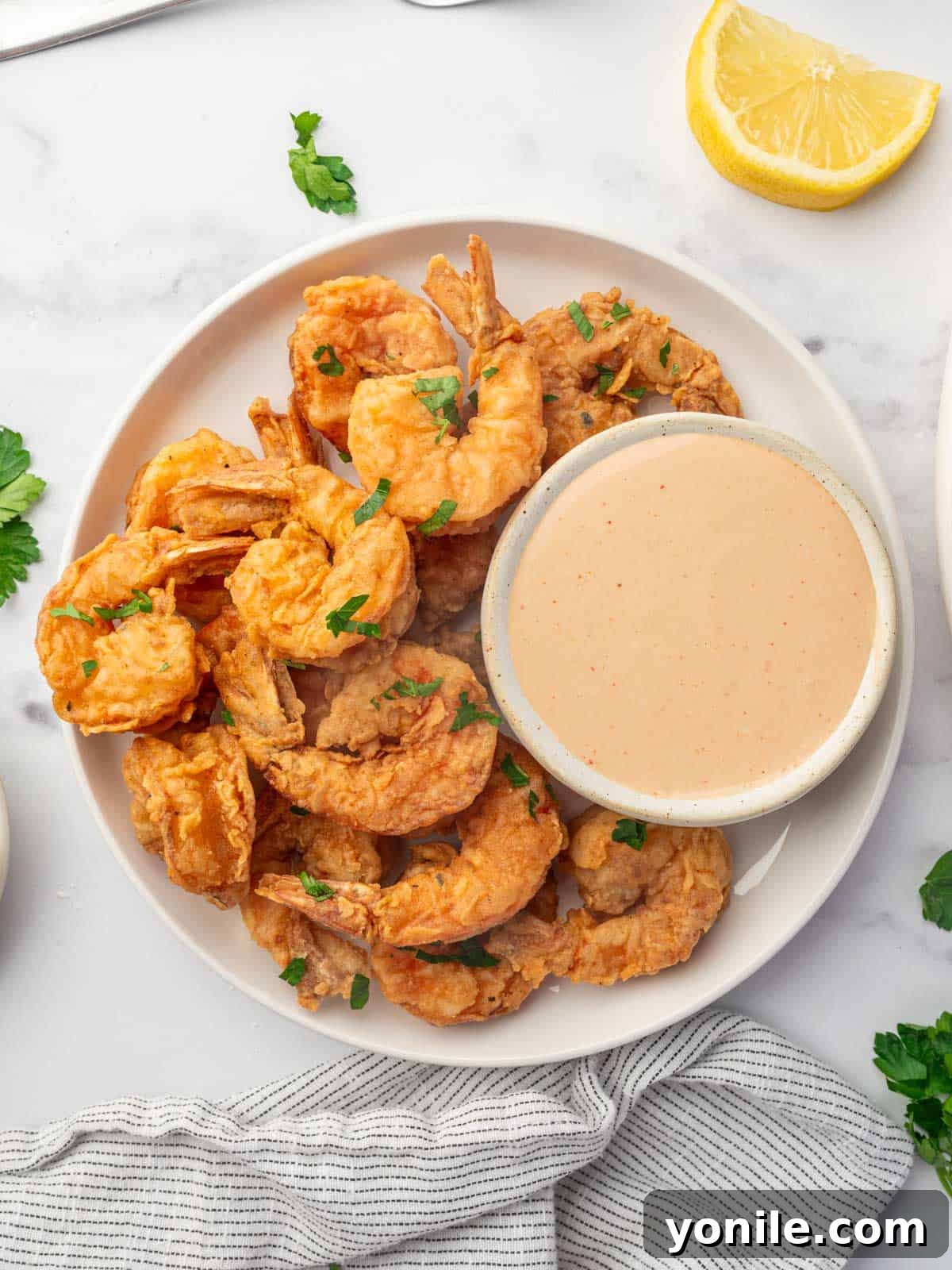 Crispy cajun shrimp on a platter with a bowl of dipping sauce.